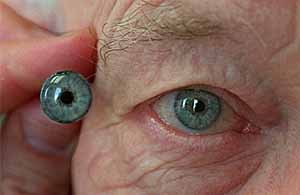 ocular 1 .28184 (7-1-98) This is tight shot of a hand painted iris disc with cornea and pupil (left). Painting the iris disc and matching it to the patient's good eye (right) is the first stage of the prostheic eye process. UT photo by Eduardo Contreras